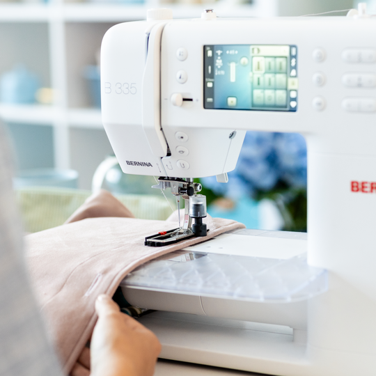 Person n&auml;ht ein helles Stoffprojekt auf der BERNINA N&auml;hmaschine B 335, Nahaufnahme mit sichtbarem Display und eingef&auml;delter Nadel image number
