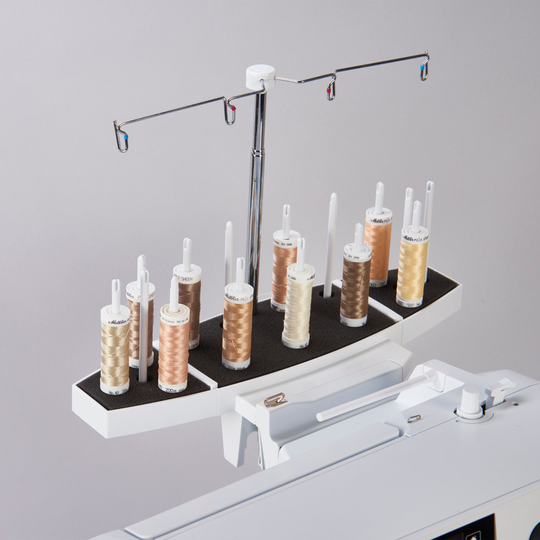 Weisser Fadenstaender auf einer BERNINA N&auml;hmaschine mit mehreren Garnrollen in Naturtoenen, zwei Metallarmen und Fadenfuehrungen vor grauem Hintergrund image number