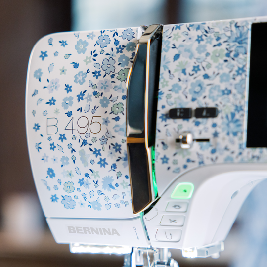 BERNINA 495 LE sewing machine with floral front design, showing control buttons and handle in a close-up view on the left side of the machine. image number