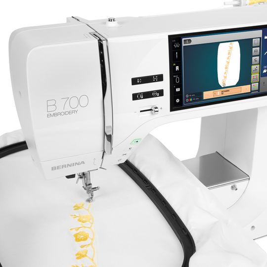 BERNINA B 700 Stickmaschine beim Sticken eines gelben Schriftzuges auf weissem Stoff, mit Farb-Touchscreen und Stickmodul in Nahaufnahme image number
