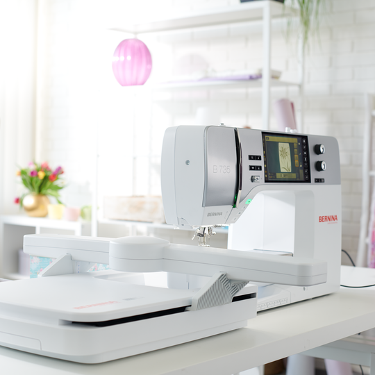 BERNINA 735 sewing and embroidery machine on a bright work table, showing large embroidery module and color touchscreen in a modern studio. image number