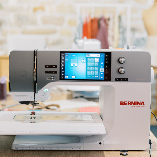 BERNINA 770 QE PLUS N&auml;hmaschine in heller Atelierumgebung, seitlich aufgenommen mit grossem Farb-Touchscreen und angebautem Verl&auml;ngerungstisch image number