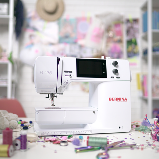 BERNINA N&auml;hmaschine B 435 in weissem Design auf kreativem, bunt dekoriertem N&auml;htisch mit Garnrollen, Stoffen und Bastelmaterial im Hintergrund image number